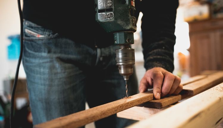 Man Drilling into a Wooden Board 